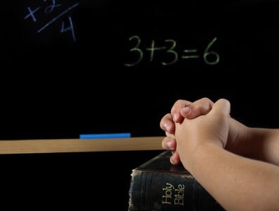 child's hand in prayer in school